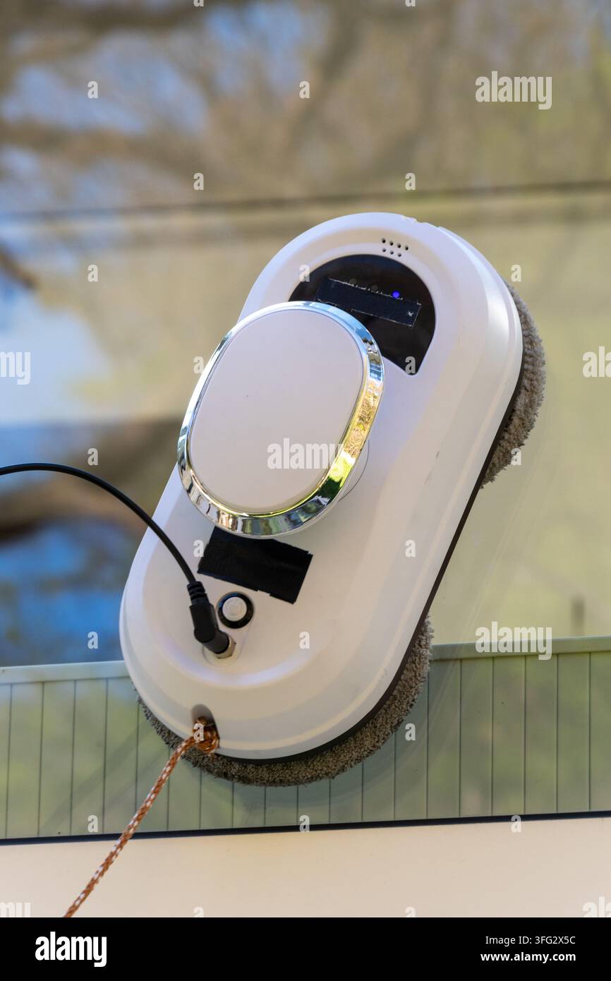 Un robot automatico per la pulizia delle finestre è attaccato a una superficie di vetro all'interno. Foto Stock