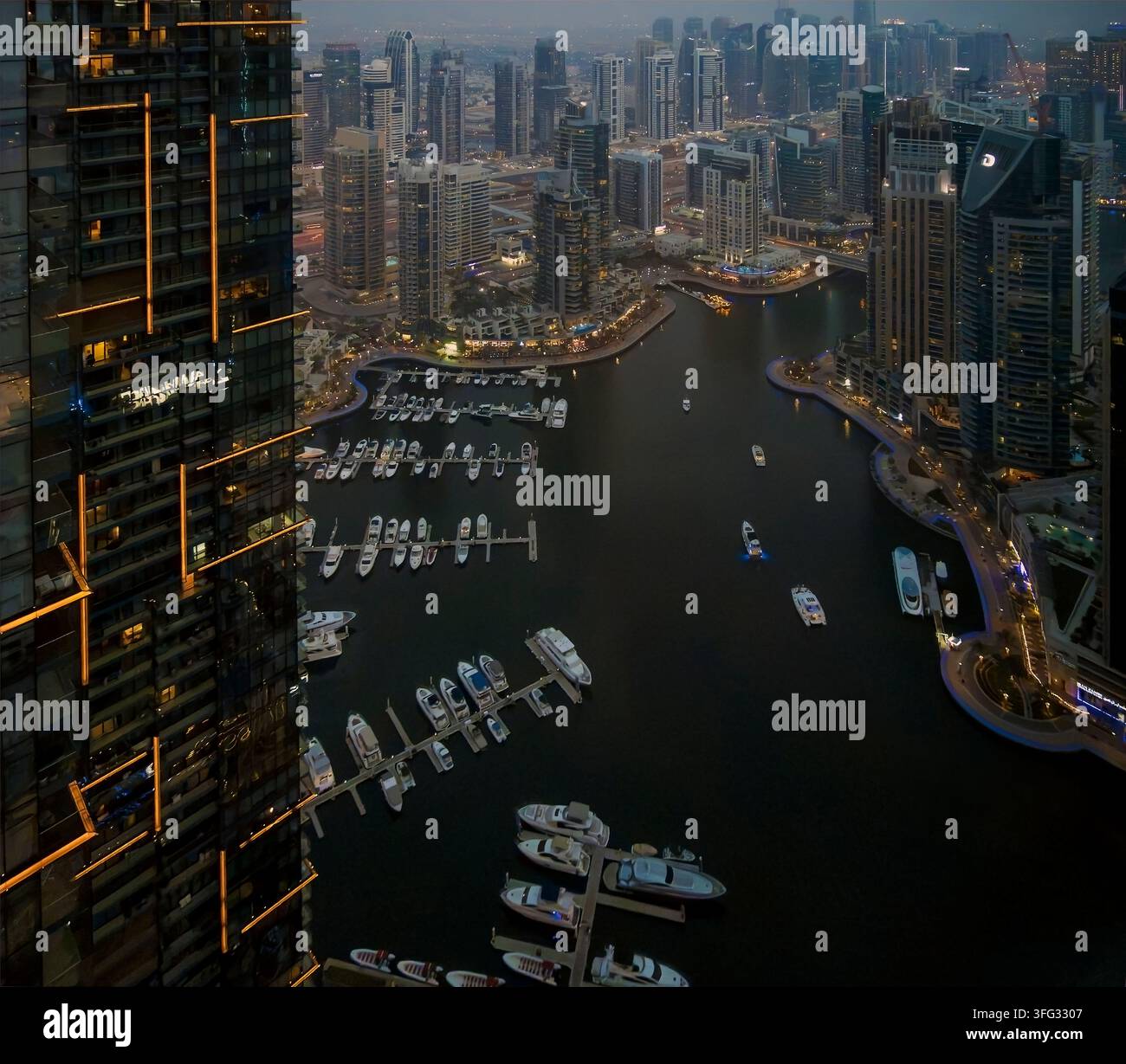 Vista elevata della Dubai Marina al crepuscolo/notte, che mostra la marina illuminata, gli yacht e i moderni grattacieli della Dubai Marina. Il lungomare si sviluppa Foto Stock