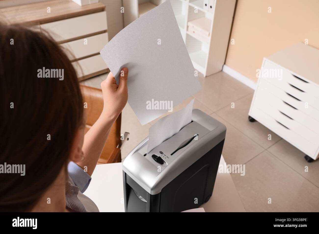 Privacy dei dati e sicurezza dei documenti, donna che distrugge documenti cartacei riservati in ufficio per prevenire il furto d'identità e proteggere le informazioni sensibili Foto Stock