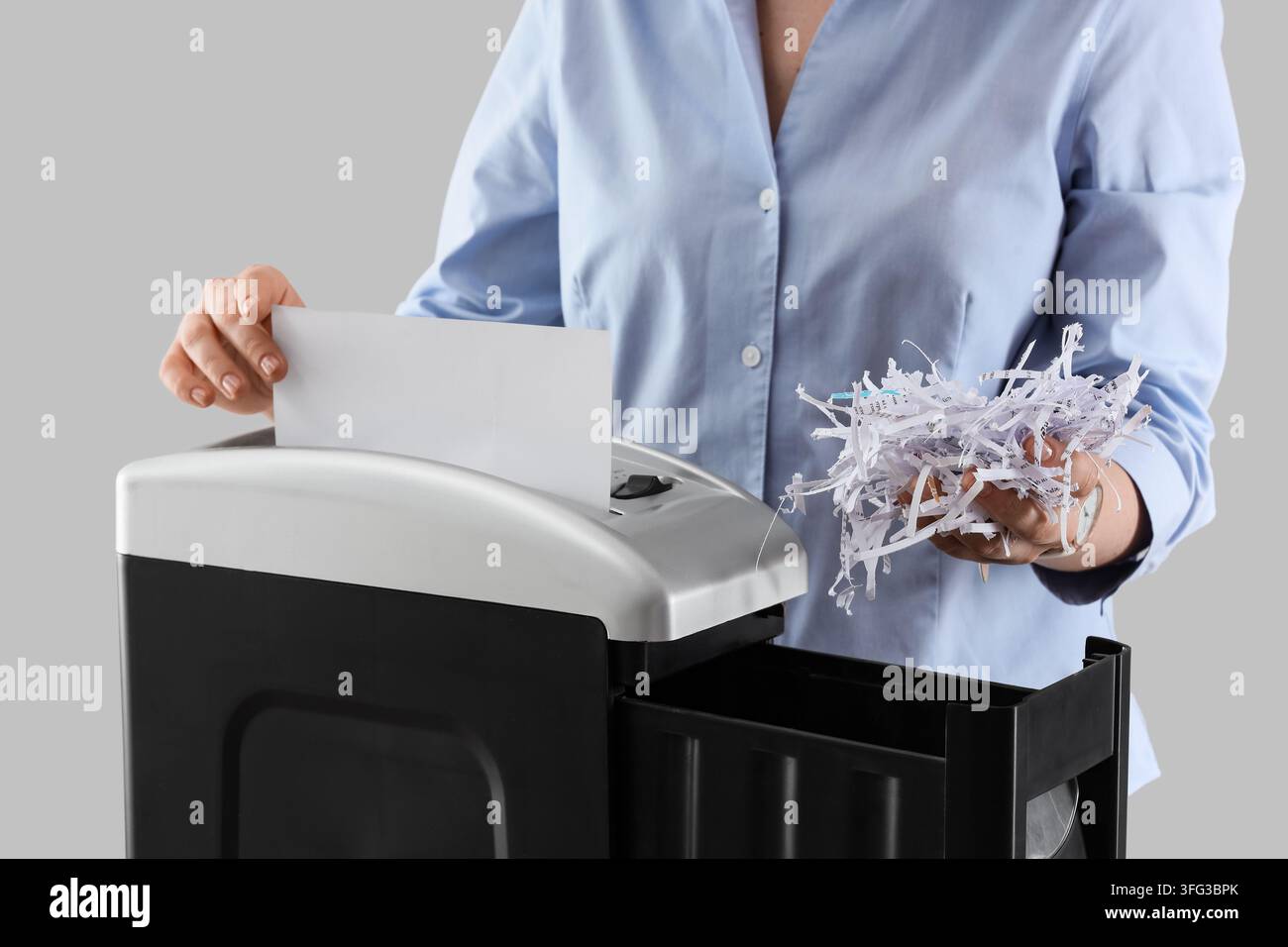 Protezione dei dati e sicurezza dei documenti, una persona distrugge carte riservate per prevenire il furto d'identità e proteggere le informazioni sensibili dell'azienda in ufficio Foto Stock