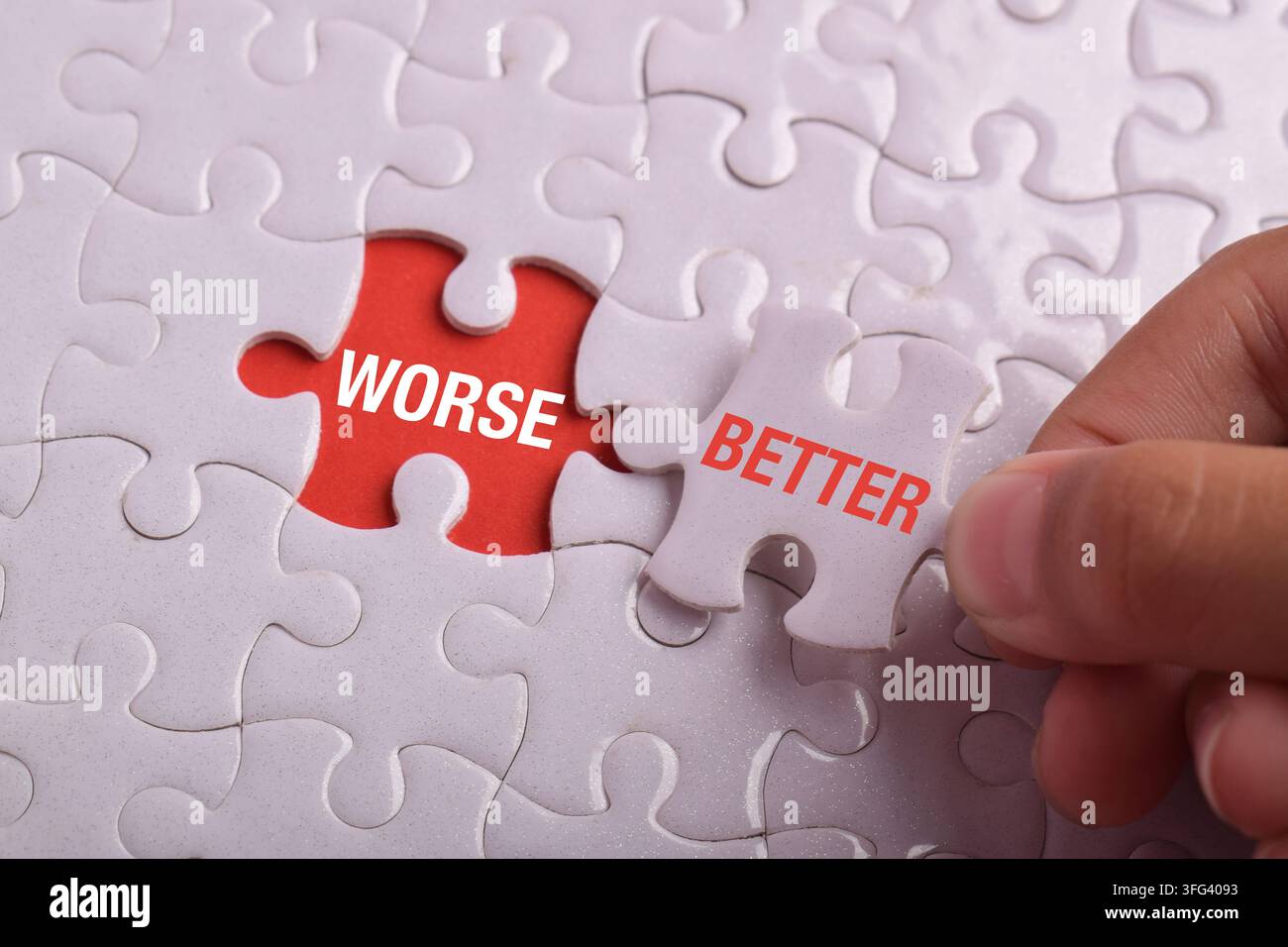 Mano che sostituisce un pezzo di puzzle peggiore con uno migliore su un puzzle bianco, simboleggiando miglioramento, cambiamento positivo, decisioni migliori, risoluzione dei problemi, crescita Foto Stock
