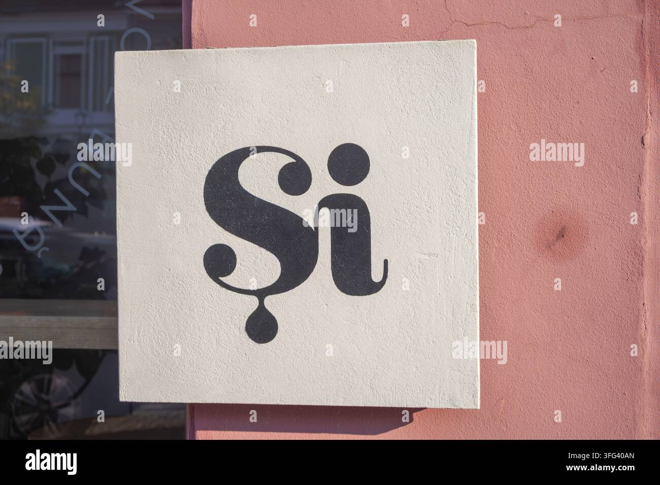 Scrittura nera stilizzata su un cartello quadrato color crema contro l'intonaco rosa - Cluj-Napoca, Romania - 14 agosto 2026. Foto Stock