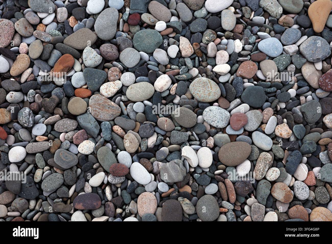 Texture di ciottoli da spiaggia, pietre lisce colorate che formano uno sfondo costiero naturale per la geologia, design organico, benessere spa, motivo a mosaico, concetti di mare. Foto Stock