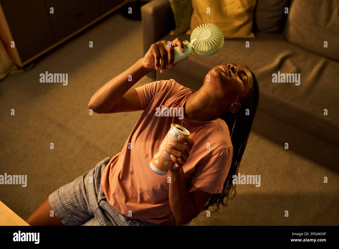 Donna nera che si rinfresca con un ventaglio portatile durante un'ondata di caldo estiva Foto Stock