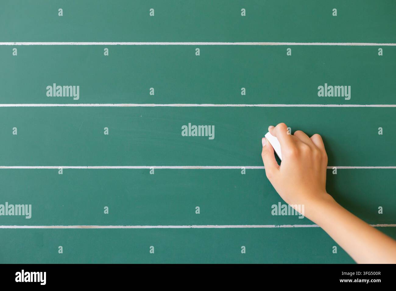 Uno studente pulisce la lavagna in un'aula scolastica durante una sessione di studio, preparandosi per le prossime lezioni e attività. Foto Stock