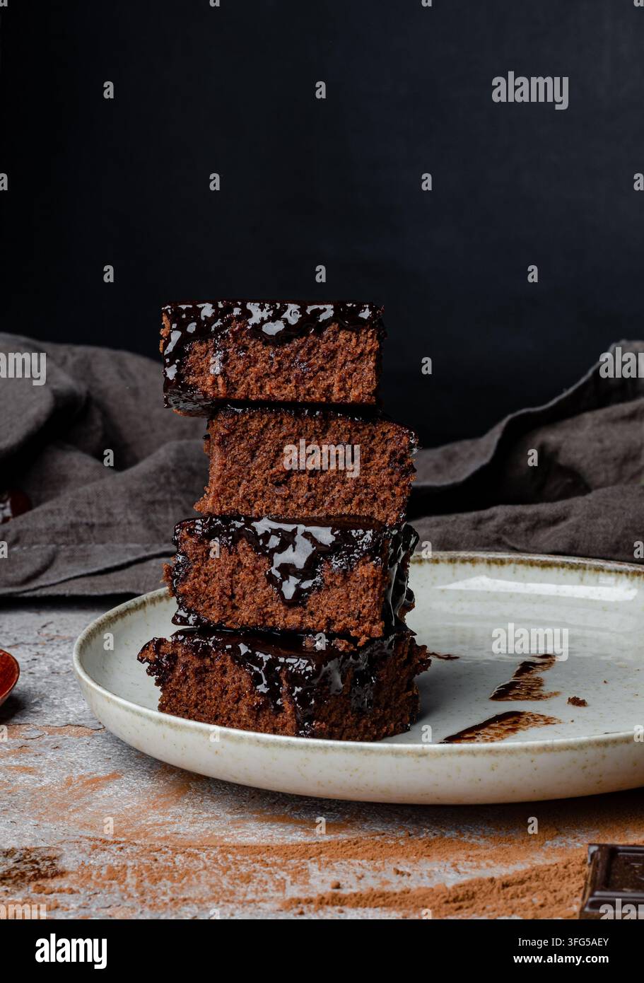 Pile di brownies al cioccolato fondente su un piatto di ceramica con basilico fresco Foto Stock