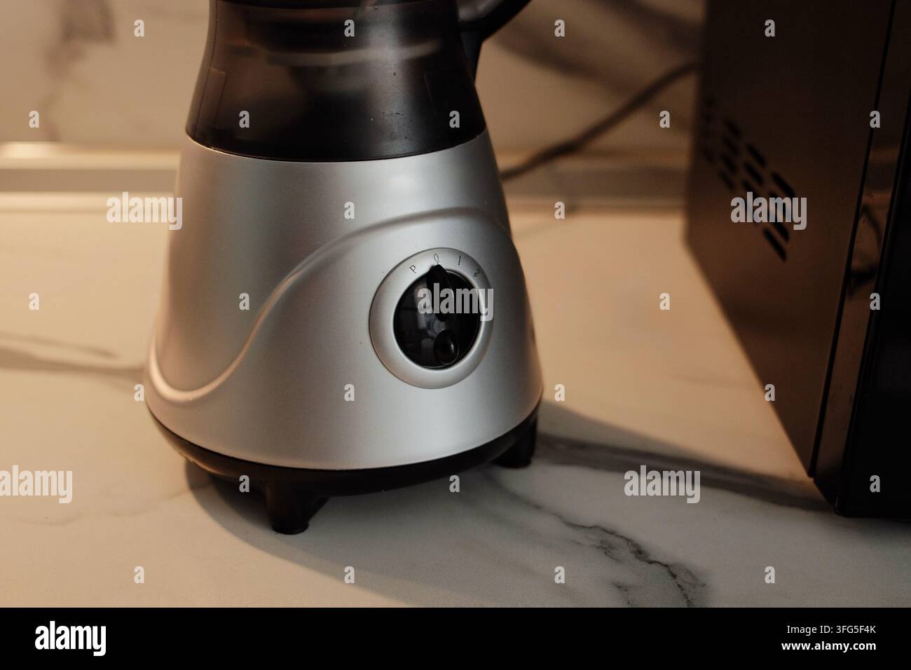 Vista dettagliata della base del frullatore sul piano di lavoro in una cucina moderna, evidenziando i controlli dell'apparecchio e la funzionalità pratica Foto Stock