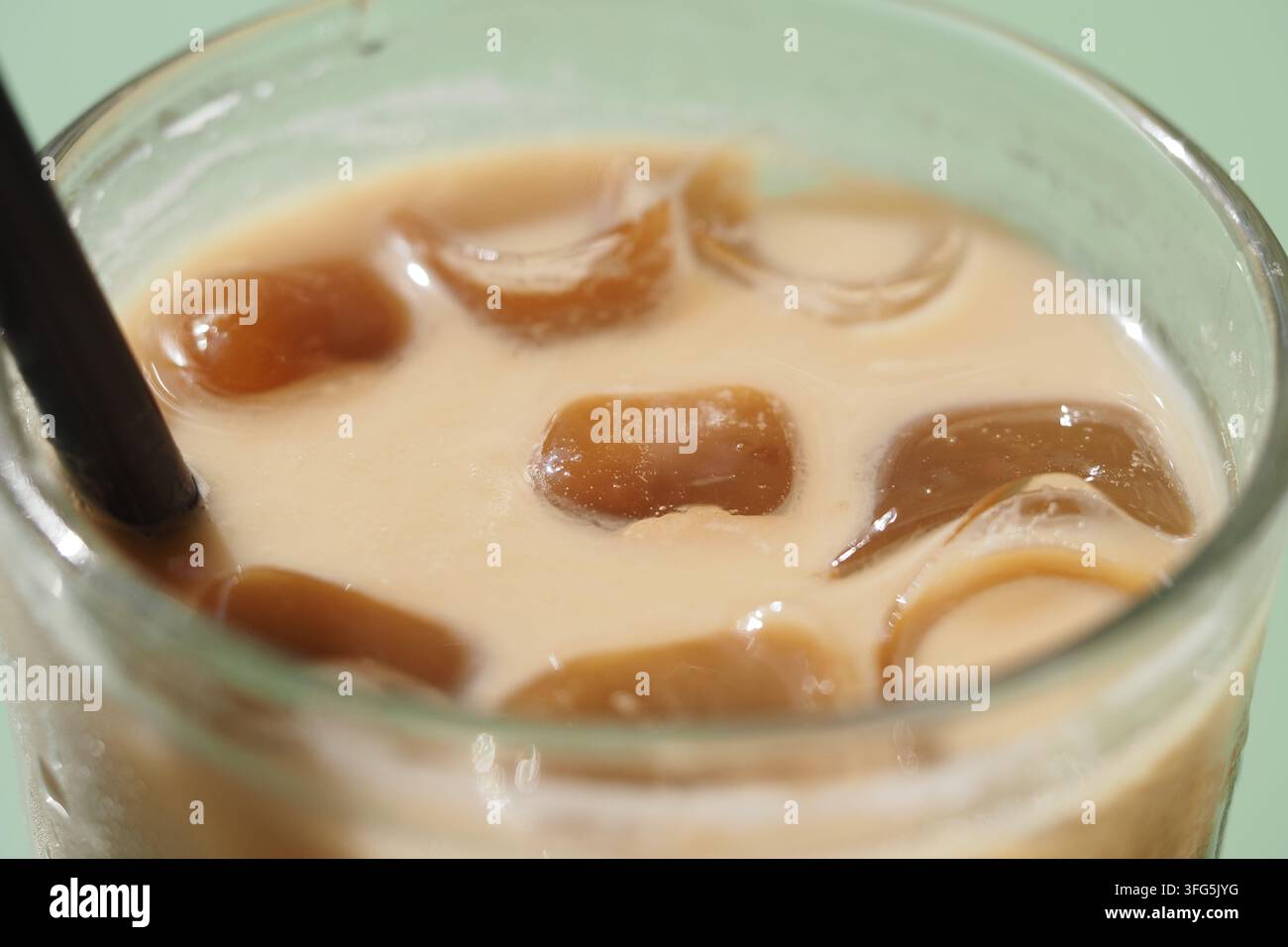 Caffè con ghiaccio in un bicchiere trasparente su un tavolo verde Foto Stock