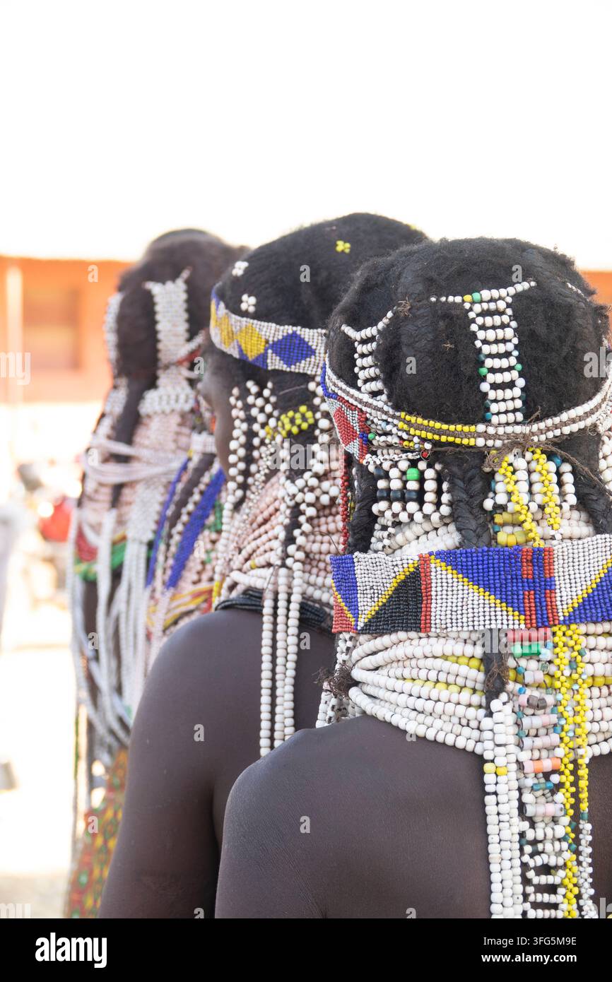 Tre donne Handa viste di spalle con copricapi e collane di perle, provincia di Huila, Hoque, Angola Foto Stock
