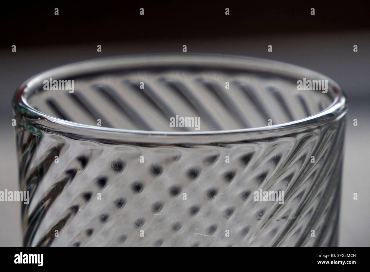 Macro di un bicchiere di vetro strutturato con motivo a spirale e riflessione della luce Foto Stock