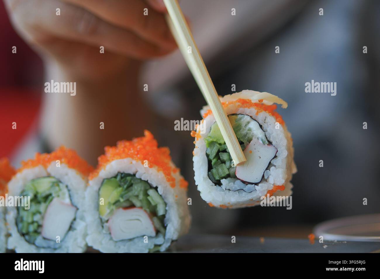 Fare involtini di sushi con le bacchette Foto Stock