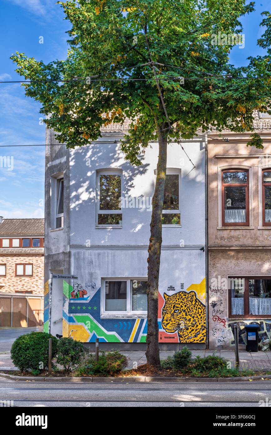 Facciata urbana luminosa con un murale geometrico audace. Foto Stock