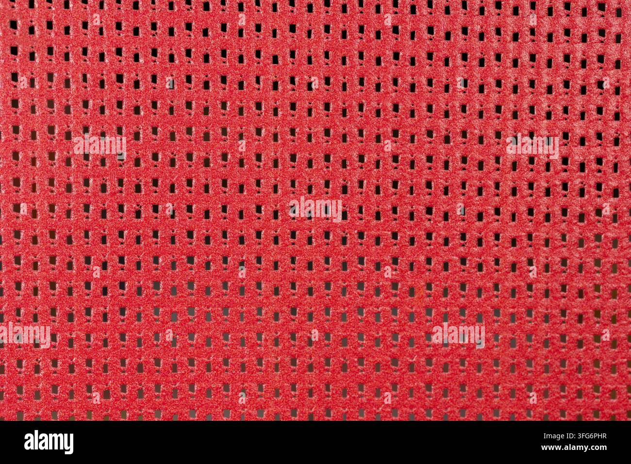 Vista dettagliata di una superficie perforata rossa con una struttura geometrica regolare. Forte sfondo astratto adatto per design, costruzione e in Foto Stock