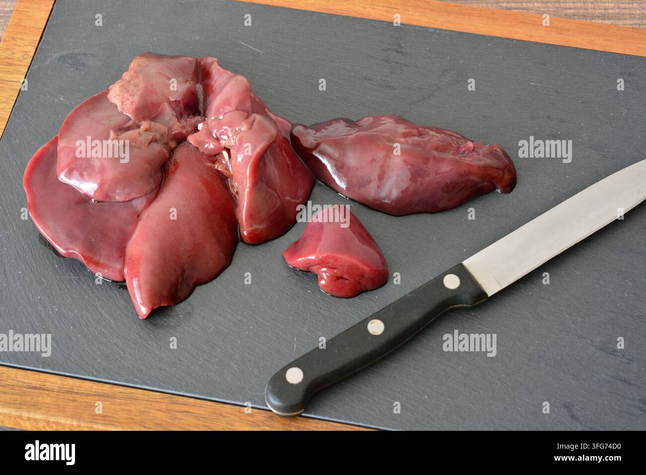 Fegato di tacchino crudo su tagliere con coltello primo piano Foto Stock