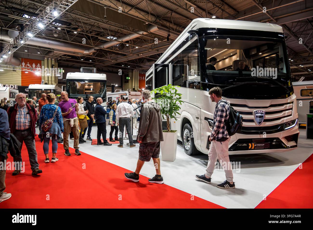 I visitatori esplorano una grande esposizione indoor che mostra veicoli ricreativi e camper moderni, evidenziando viaggi e tempo libero Foto Stock