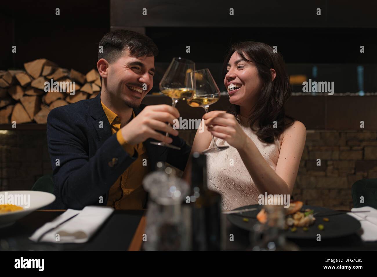 Una coppia felice celebra un'occasione speciale brindando con bicchieri di vino in un ristorante. Foto Stock