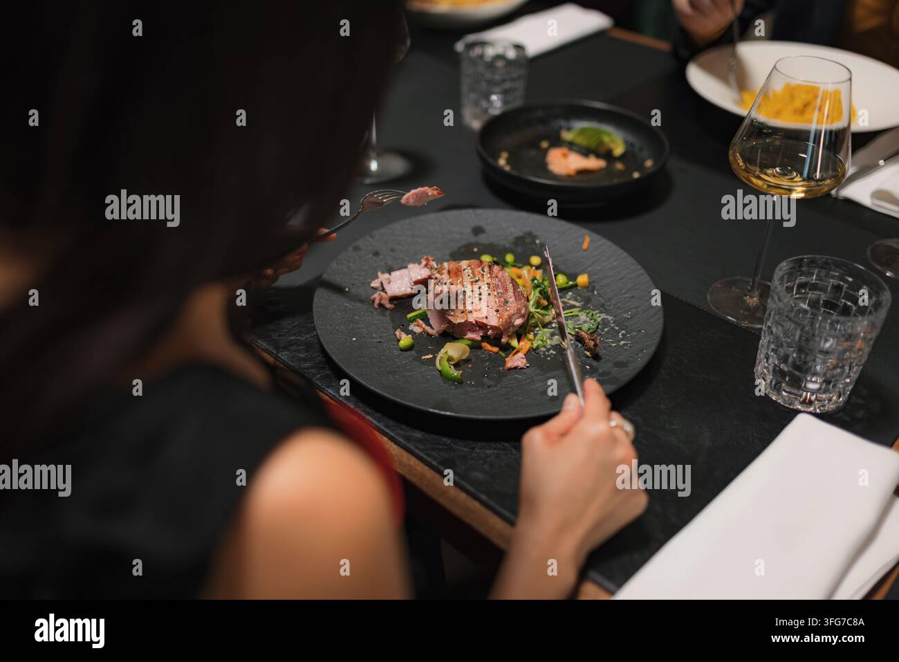 Donna che si gode il suo pasto gourmet in un ristorante di alta cucina con amici. Foto Stock