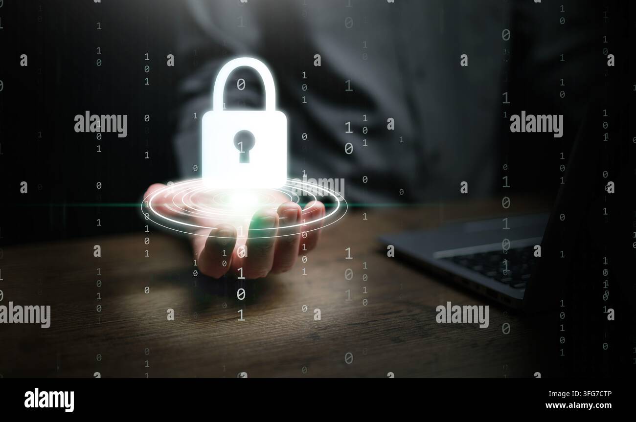 Concetto di cybersecurity. Una mano maschile accanto a un laptop sul suo tavolo da lavoro in ufficio che tiene un'icona di lucchetto luminosa sopra la scrivania per la protezione del sistema e la sicurezza Foto Stock