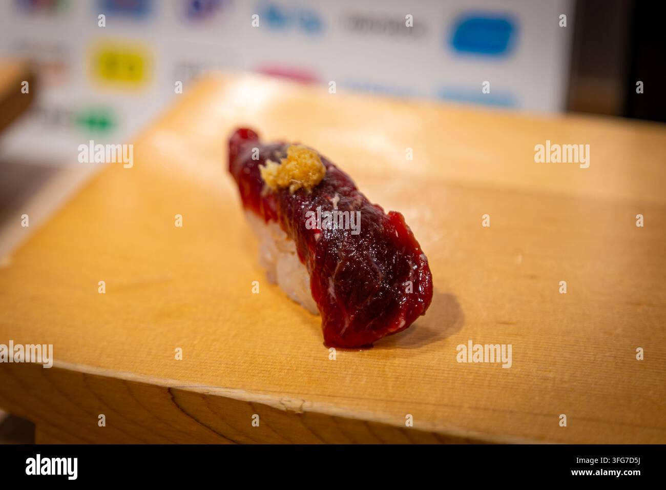 Sushi nigiri al Kujira ricoperto di zenzero grattugiato servito su un vassoio tradizionale in legno geta in un ristorante giapponese. È una delizia stagionale Foto Stock
