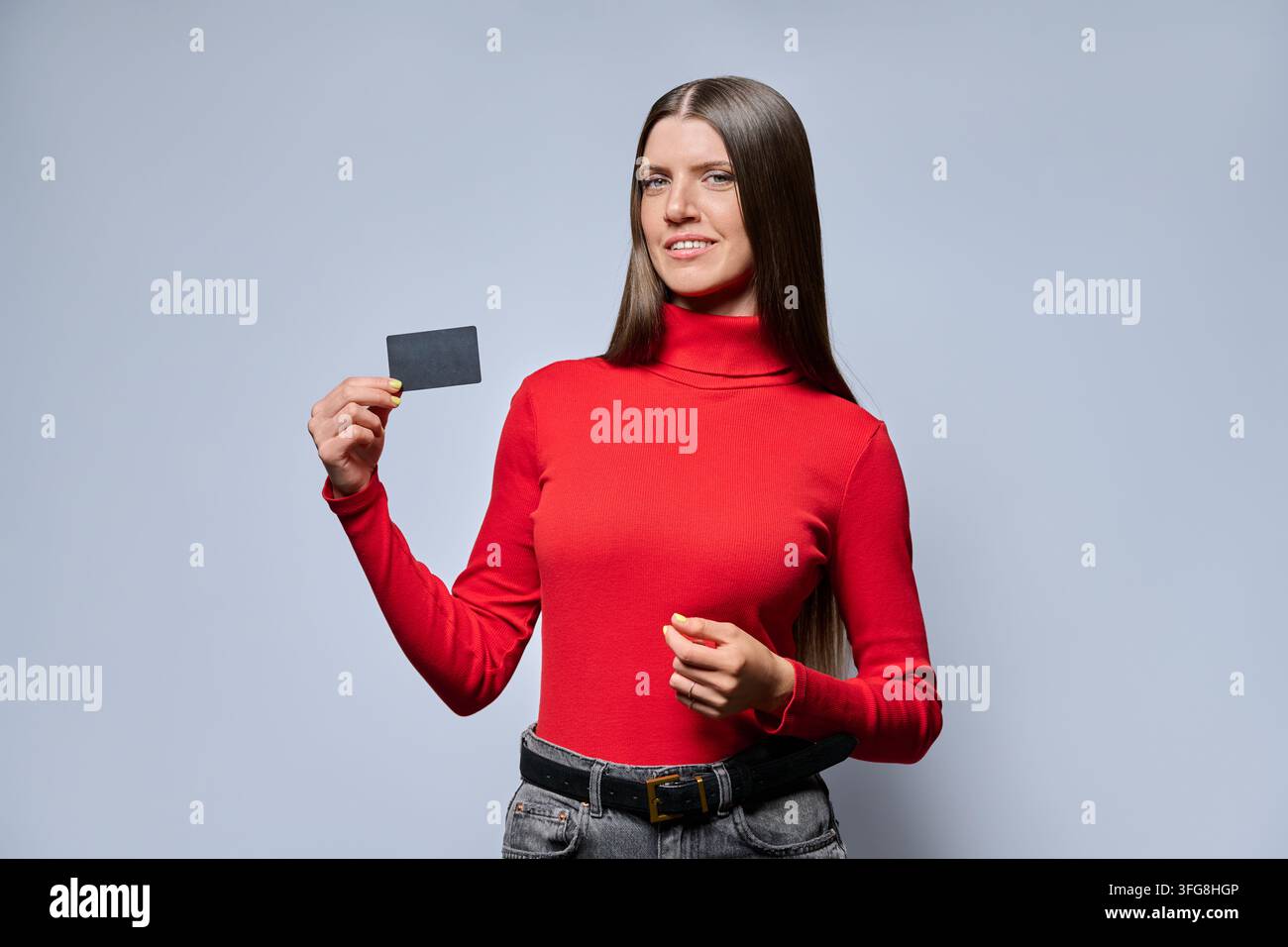 Giovane donna che mostra una carta di plastica vuota in un ritratto in studio Foto Stock