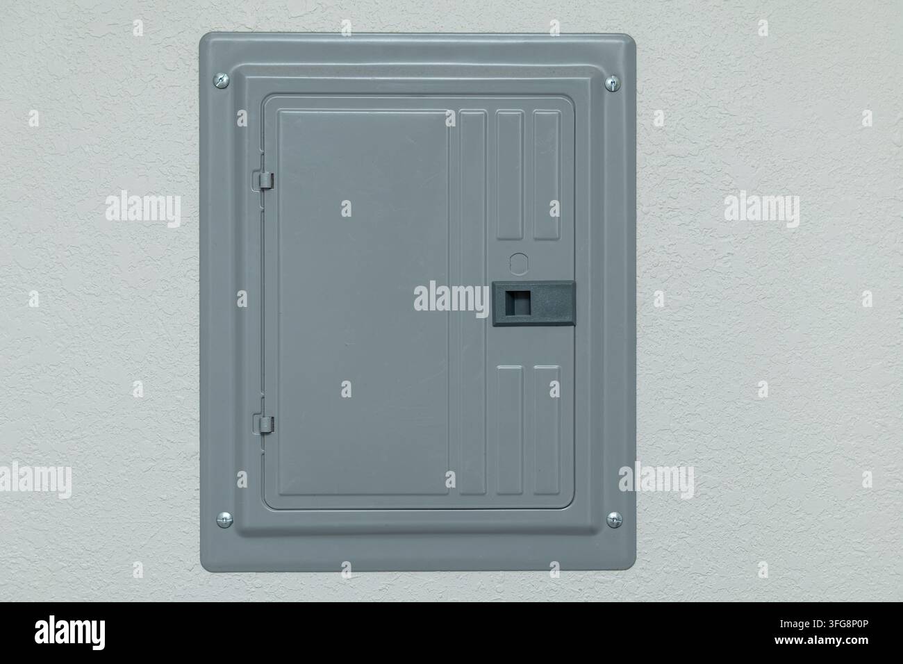 Copertura del pannello elettrico in metallo grigio montata su muro ruvido con viti, cerniere, chiavistello e porta di accesso rettangolare Foto Stock