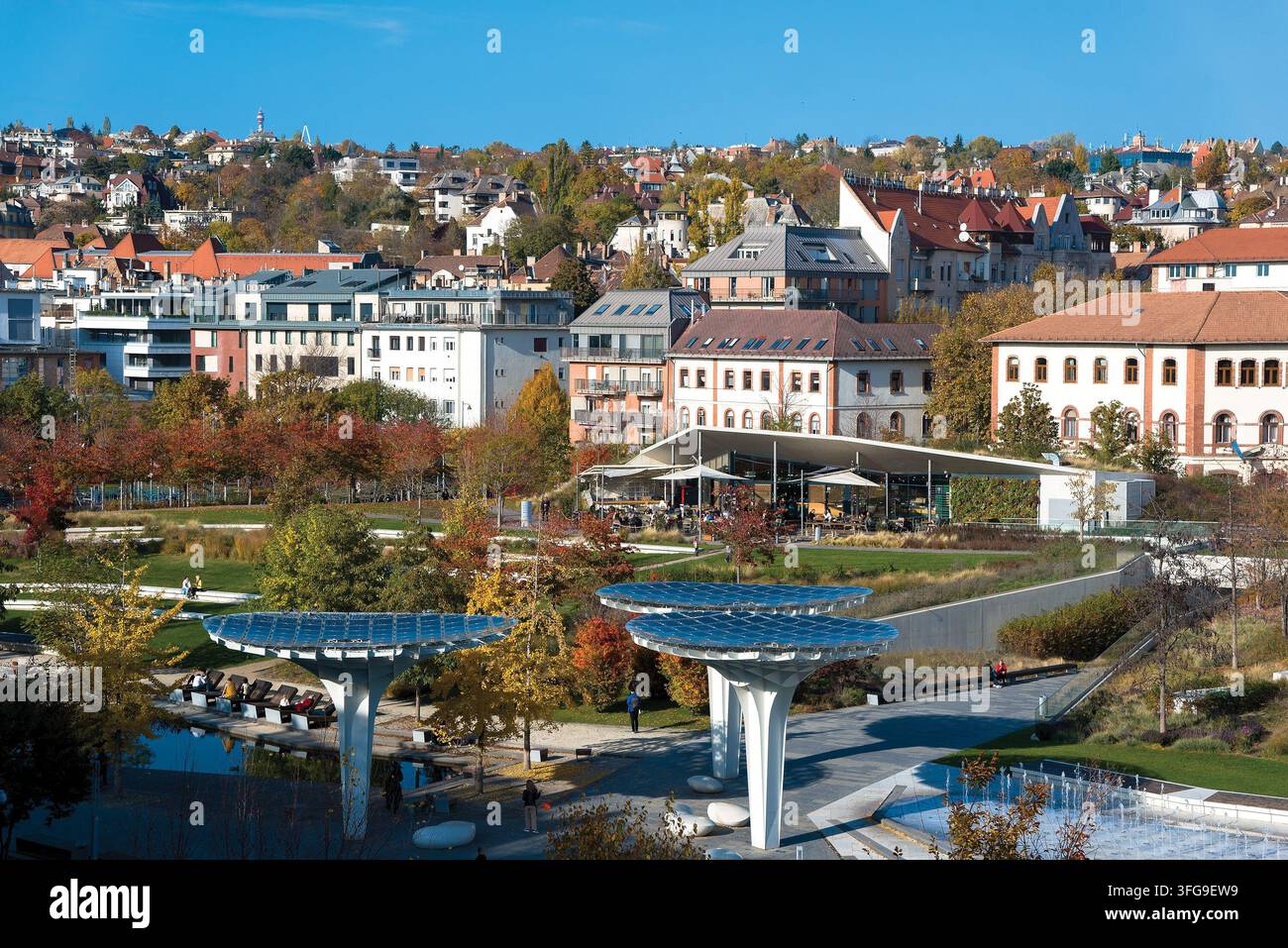 Vista panoramica del parco Millenariss a Budapest con strutture solari ad albero, architettura urbana moderna e paesaggio autunnale sotto un cielo blu terso Foto Stock