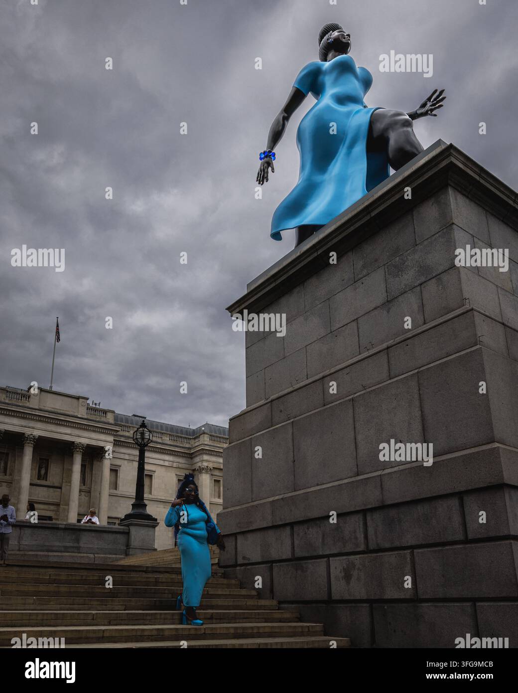 Signora in blu di Tschabalala Self sul Fourth Plinth accompagnata da un turista di passaggio in colori simili a Trafalgar Square, Londra. Foto Stock