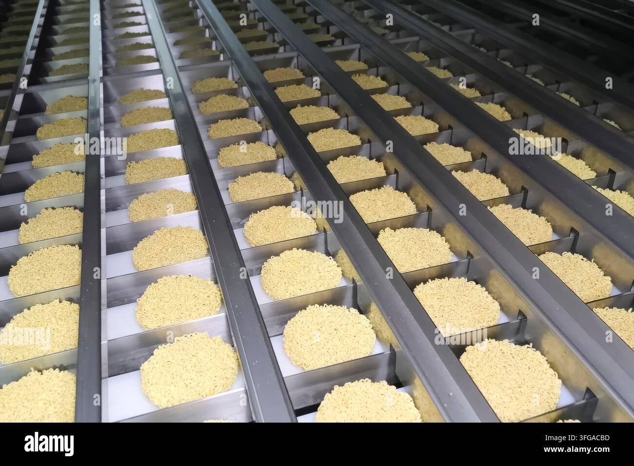Linea di produzione istantanea di spaghetti. porzioni di spaghetti sul trasportatore, industria alimentare di massa. Foto Stock