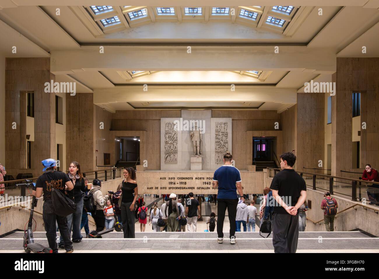 Bruxelles, Belgio – 26 agosto 2026: Visitatori scendono ampie scale all'interno di una hall della stazione centrale a Bruxelles con pareti in pietra, lucernari, scu Foto Stock