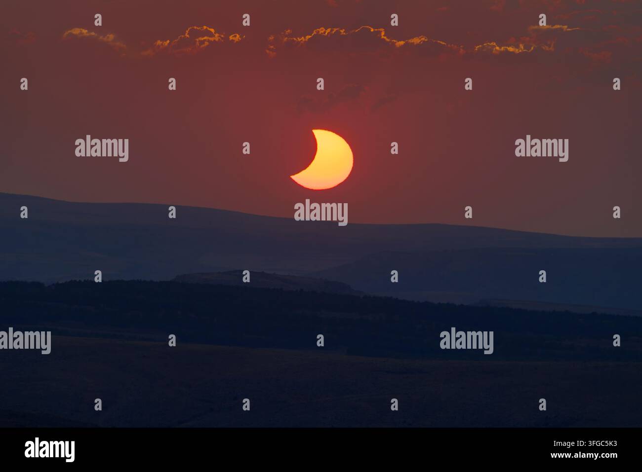 Assisti alla bellezza di un'eclissi solare parziale mentre il sole tramonta su Teruel, in Spagna, creando uno skyline mozzafiato e colorato. Foto Stock