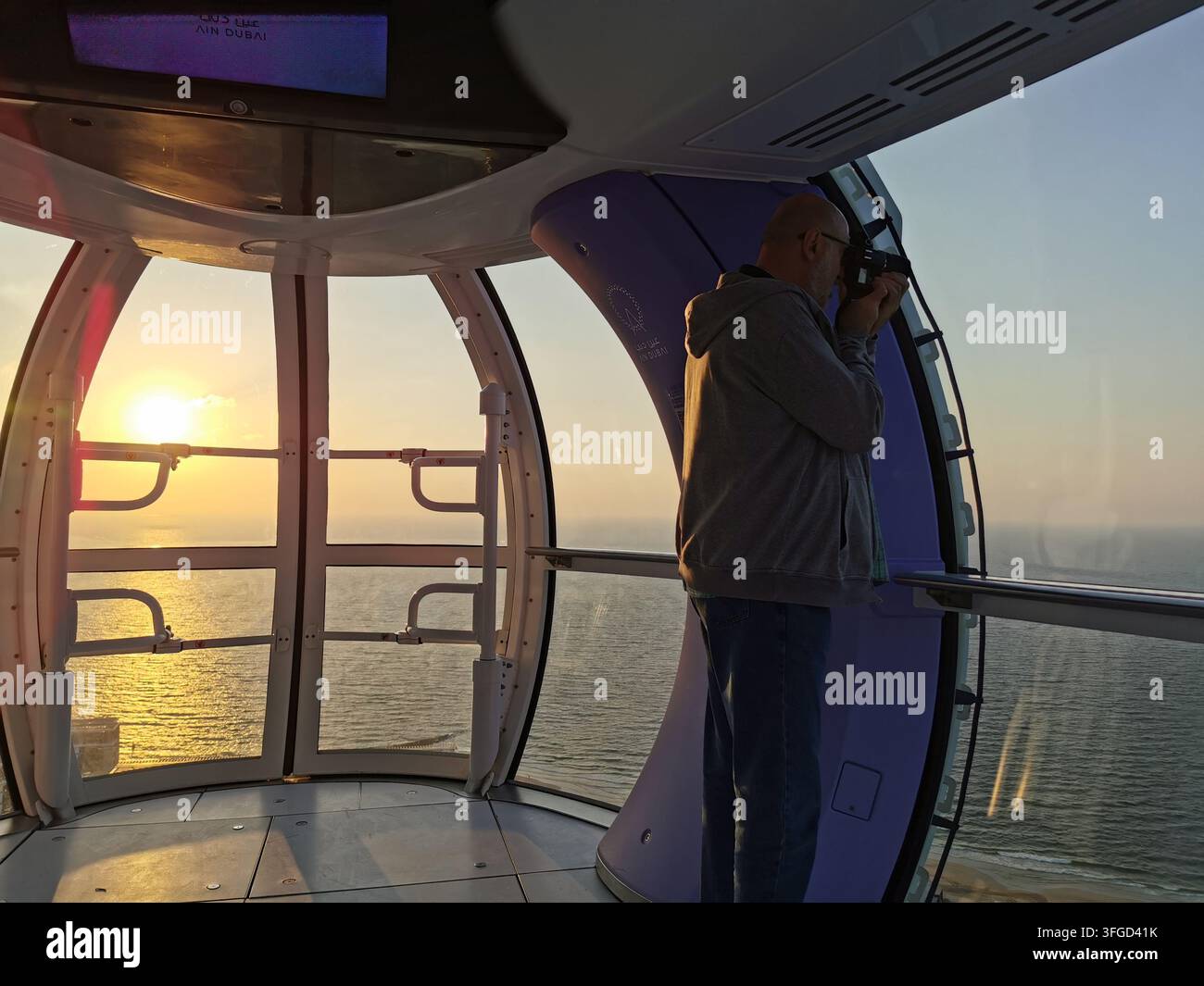 DUBAI, EMIRATI ARABI UNITI - 30 GENNAIO 2026: Un visitatore fotografa il tramonto da una cabina di osservazione dell'Ain Dubai che si affaccia sul Golfo Arabico. Foto Stock