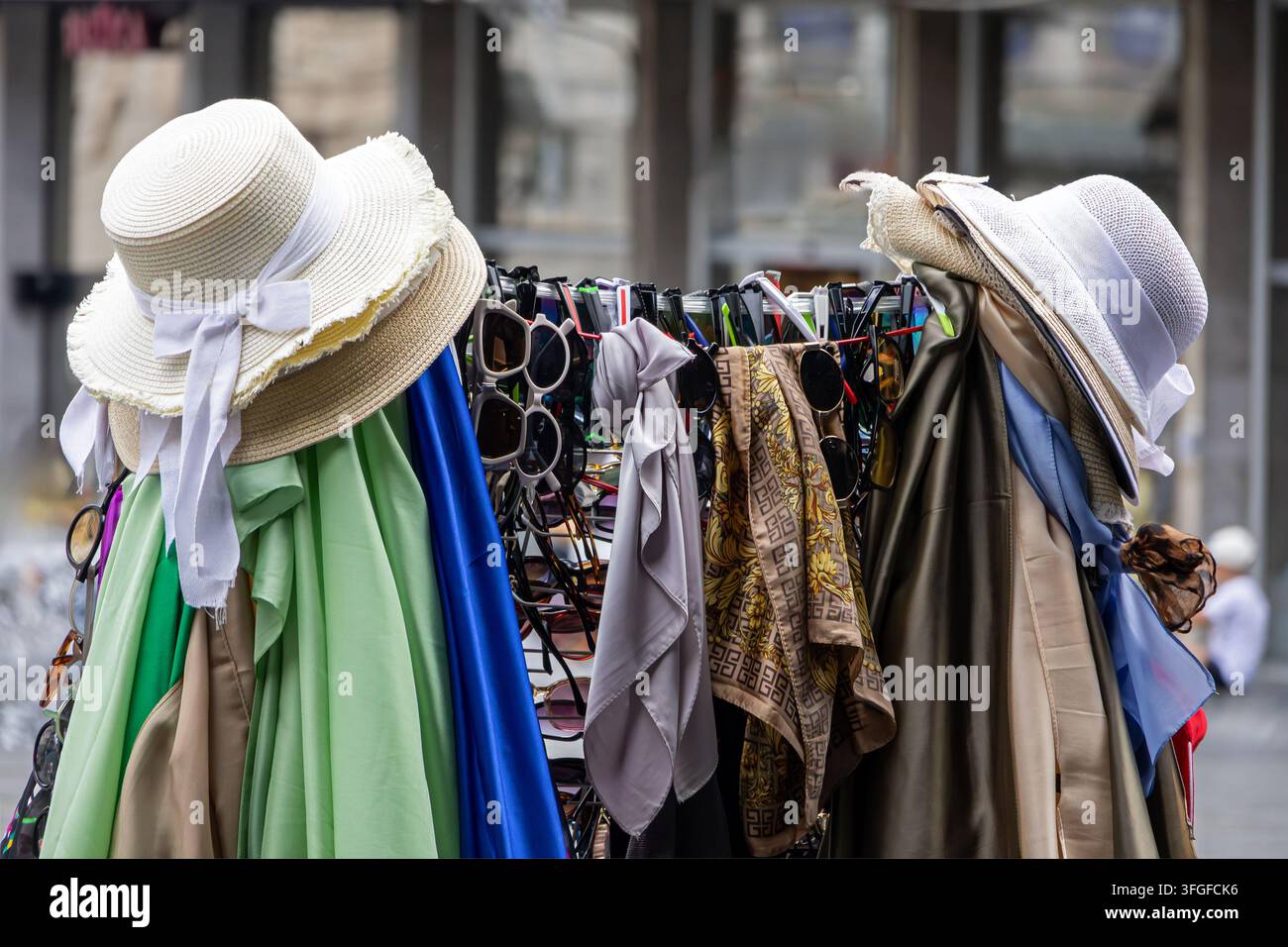 Accessori piccoli alla moda femminili, cappelli e sciarpe all'esterno su una bancarella del mercato di strada in città Foto Stock