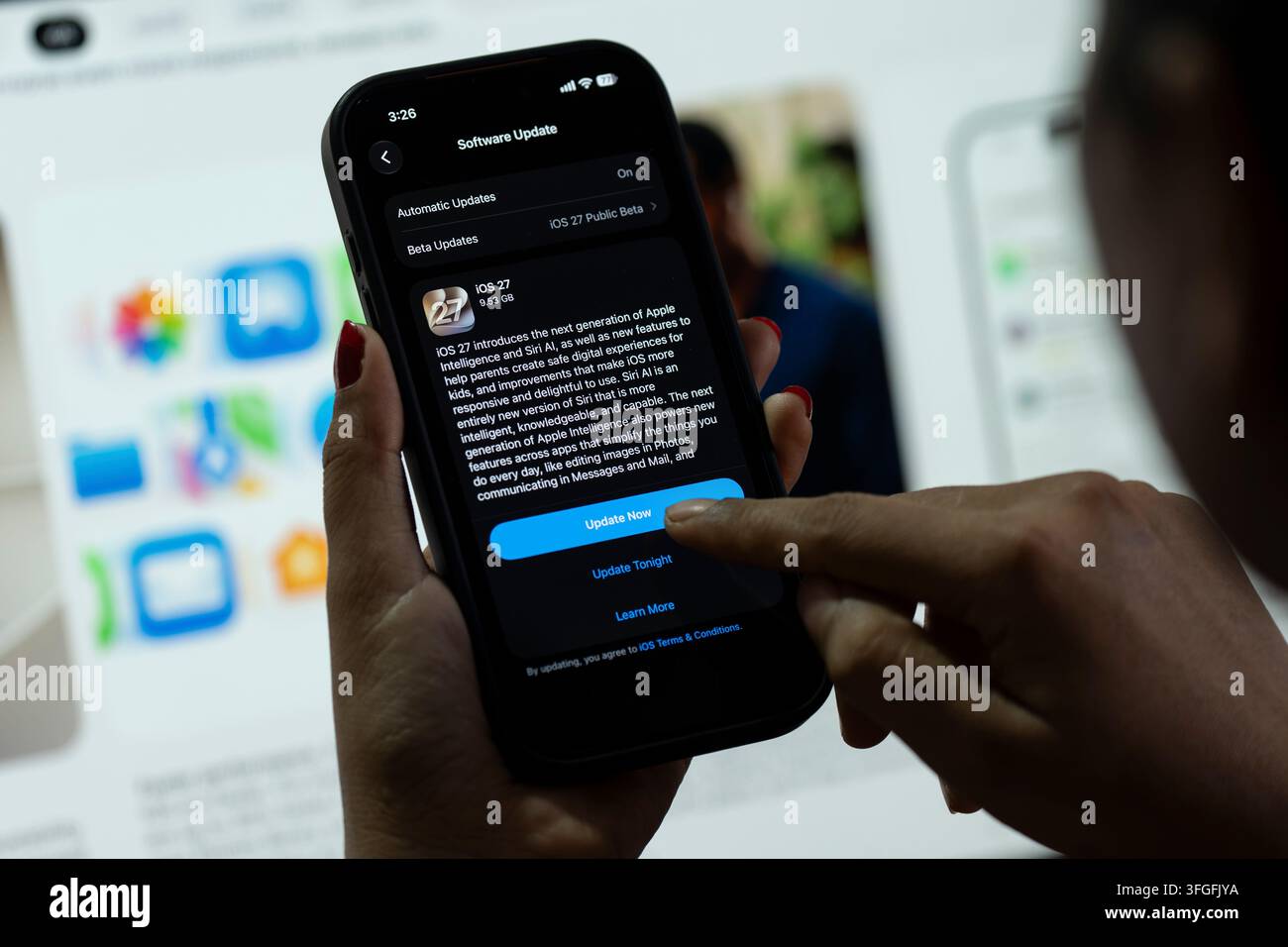 In questa illustrazione fotografica, una persona preme il pulsante "Aggiorna ora" su un iPhone che mostra lo schermo dell'aggiornamento software iOS 27, evidenziando l'ultima novità di Apple Foto Stock