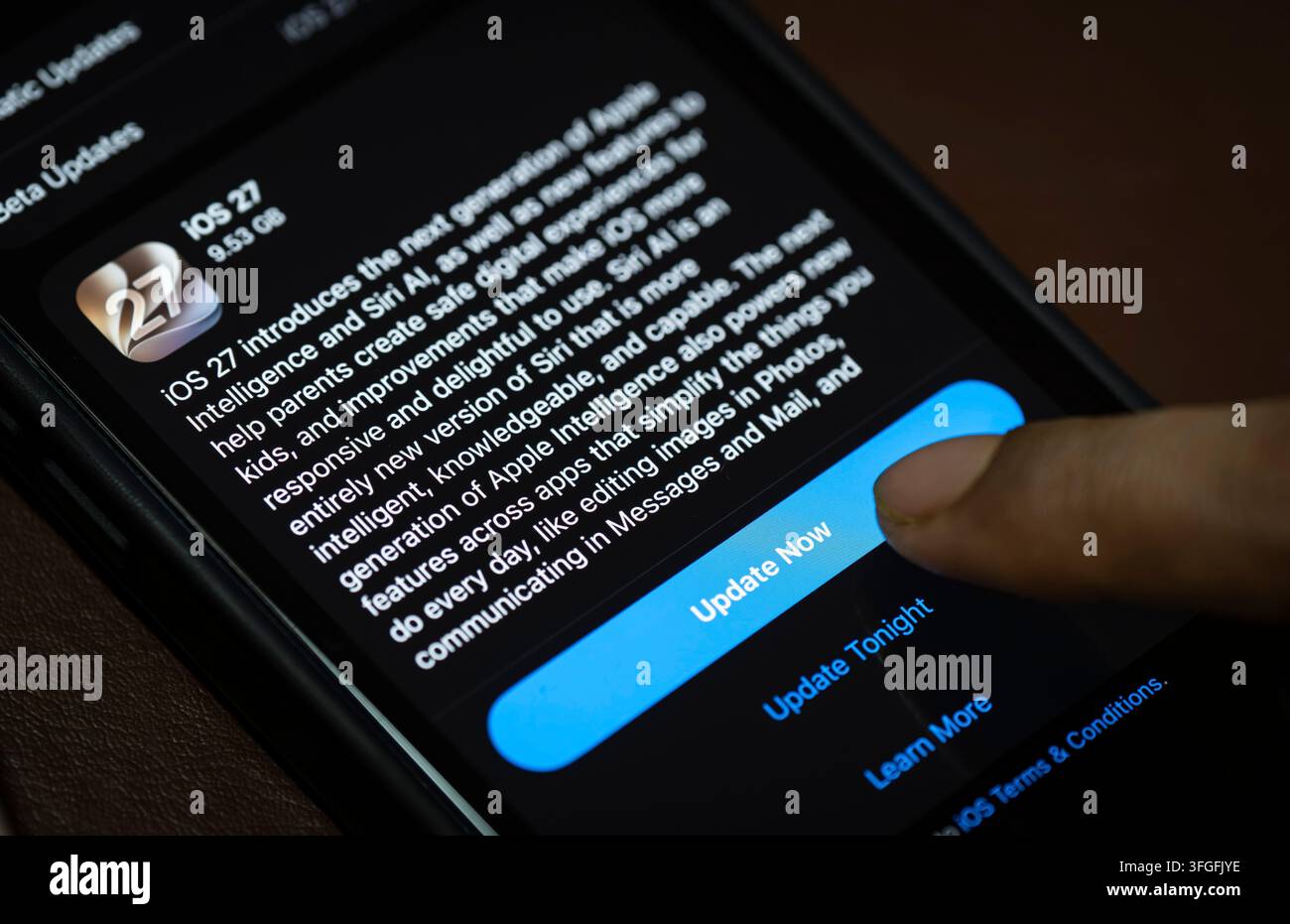 In questa illustrazione fotografica, una persona preme il pulsante "Aggiorna ora" su un iPhone che mostra lo schermo dell'aggiornamento software iOS 27, evidenziando l'ultima novità di Apple Foto Stock