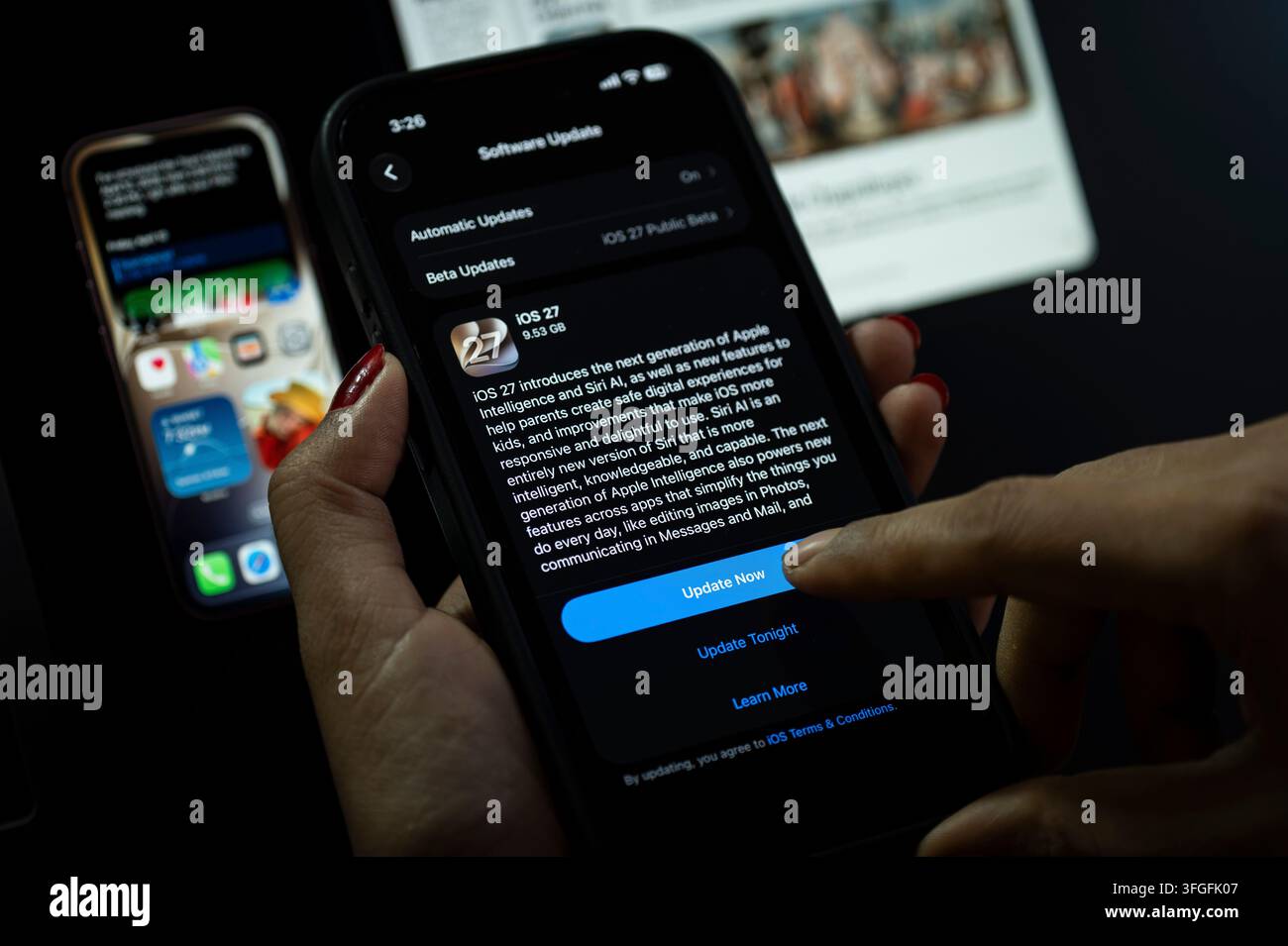 In questa illustrazione fotografica, una persona preme il pulsante "Aggiorna ora" su un iPhone che mostra lo schermo dell'aggiornamento software iOS 27, evidenziando l'ultima novità di Apple Foto Stock