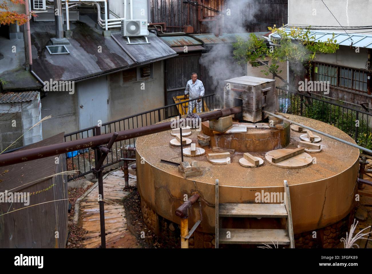 Operaio di manutenzione giapponese che controlla la sorgente termale fumante Gosho (御所泉源) nella località termale di Arima Onsen (有馬温泉), Kobe, Hyogo, Giappone. Foto Stock