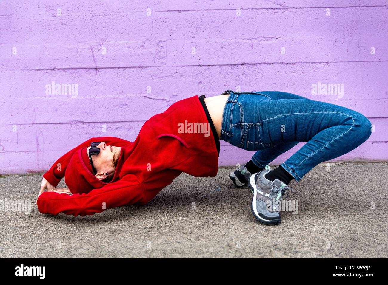 Persona flessibile che esegue un esercizio di allungamento in iperestensione sulla strada urbana Foto Stock