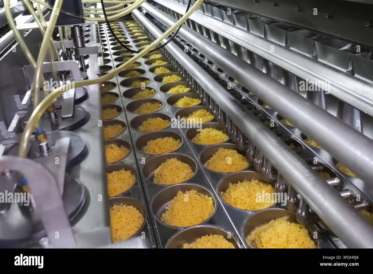 Linea di produzione istantanea di spaghetti. porzioni di spaghetti sul trasportatore, industria alimentare di massa. Foto Stock