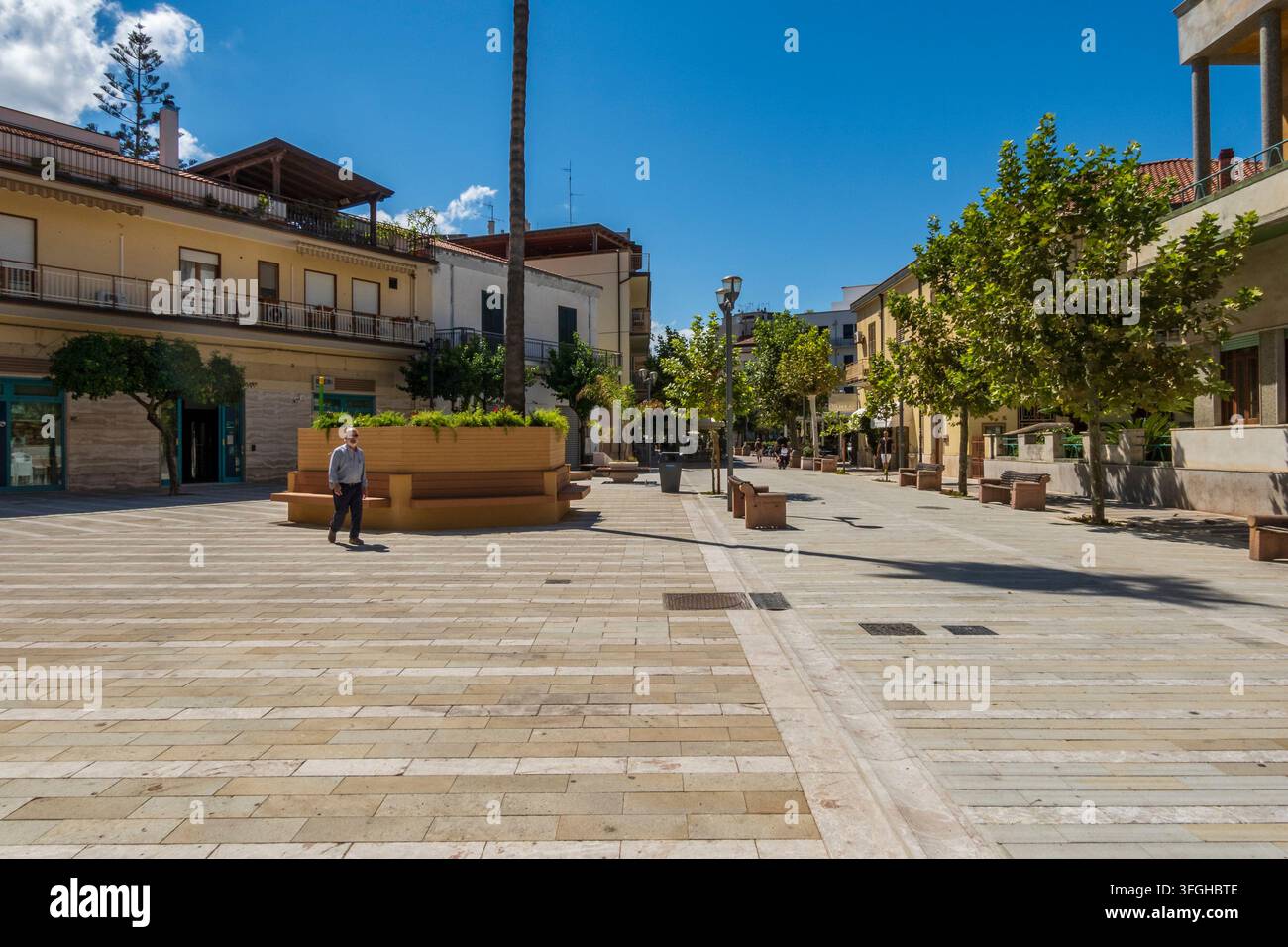 Capo d'Orlando, ME - IT - 4 set 2026: Una vista prospettica di una piazza pedonale lastricata con piastrelle di pietra, con grandi panchine in legno a forma di aiuole, Foto Stock