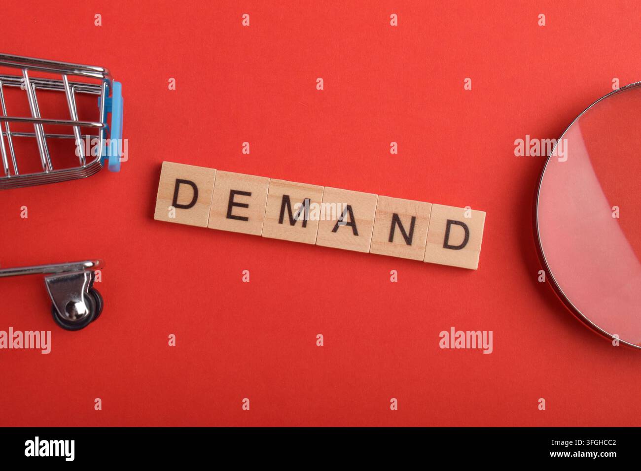 Concetto di domanda con tessere di lettere, carrello della spesa e lente d'ingrandimento su sfondo rosso, rappresentante la domanda dei consumatori e le tendenze del mercato Foto Stock