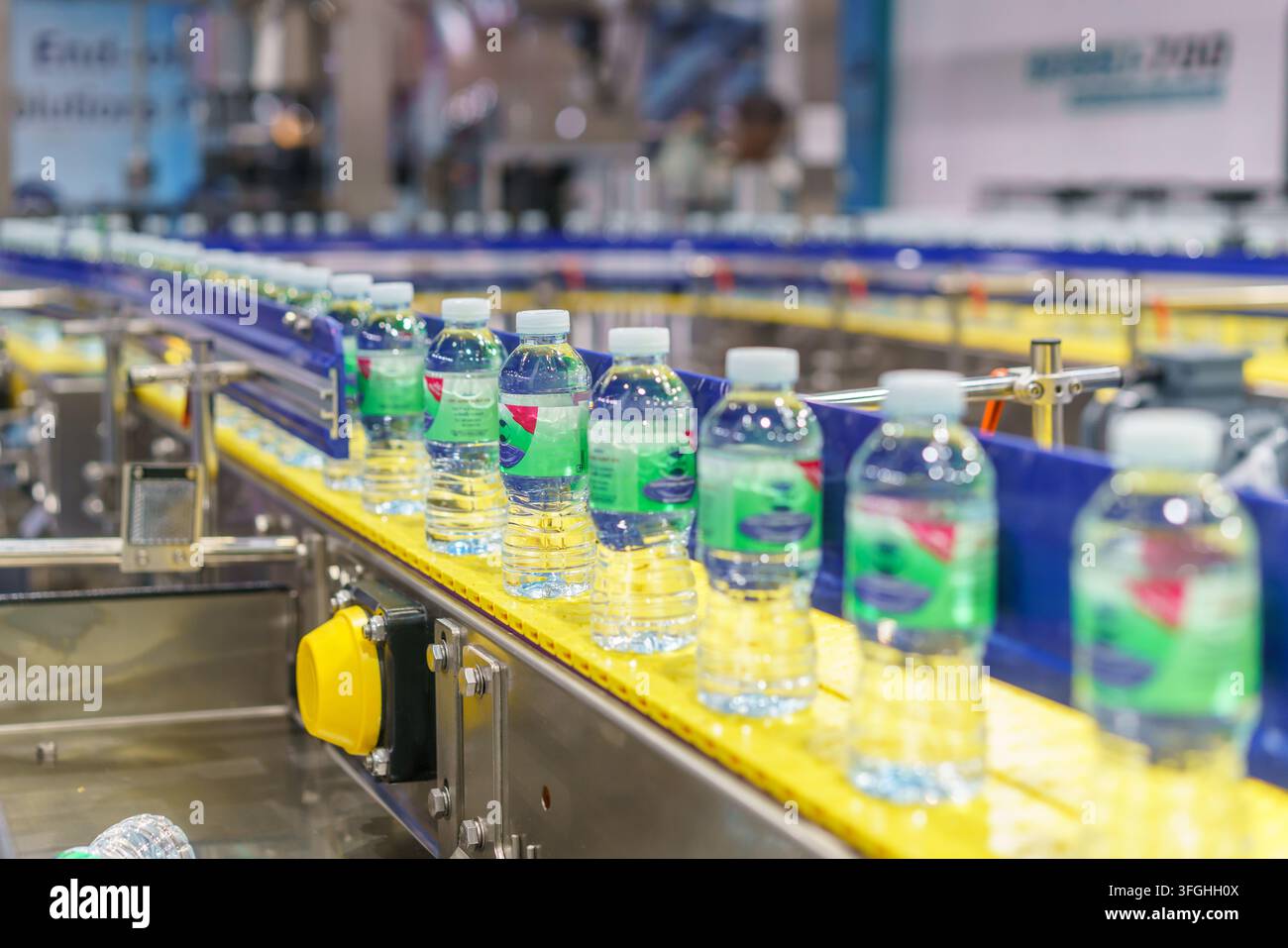 Centinaia di bottiglie di plastica trasparente piene di acqua potabile fresca che si muovono su un nastro trasportatore curvo su una linea di produzione automatizzata all'interno di un moderno Foto Stock