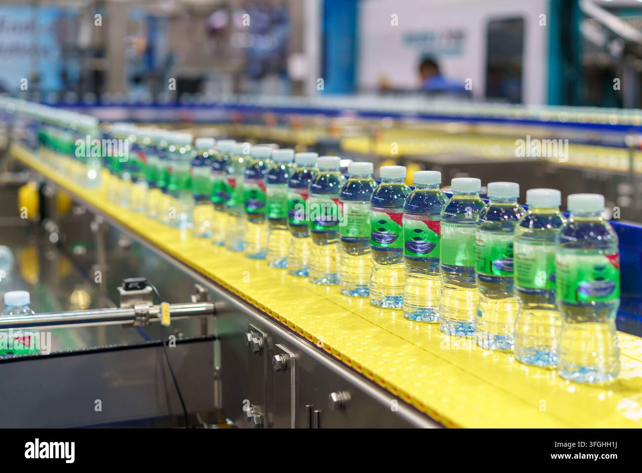 Centinaia di bottiglie di plastica trasparente piene di acqua potabile fresca che si muovono su un nastro trasportatore curvo su una linea di produzione automatizzata all'interno di un moderno Foto Stock