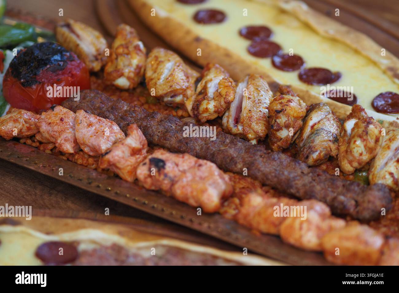 Piatto di kebab misto grigliato con spiedini di pollo, kebab turco e pane pide su vassoio di legno Foto Stock