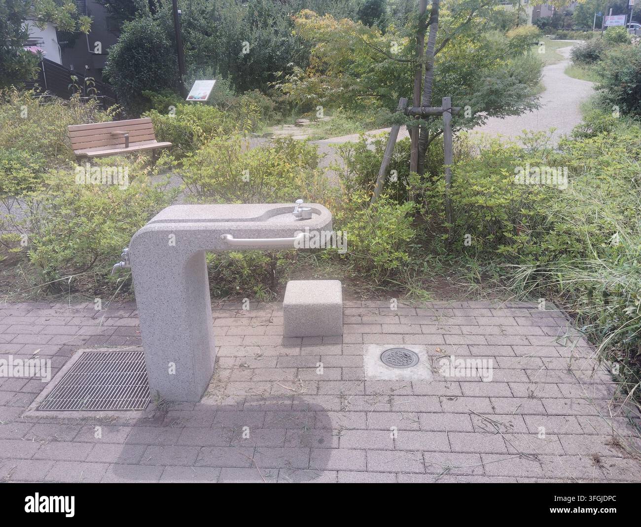 Fontana pubblica circondata dalla vegetazione in un piccolo parco di quartiere a Tokyo, Giappone. Foto Stock