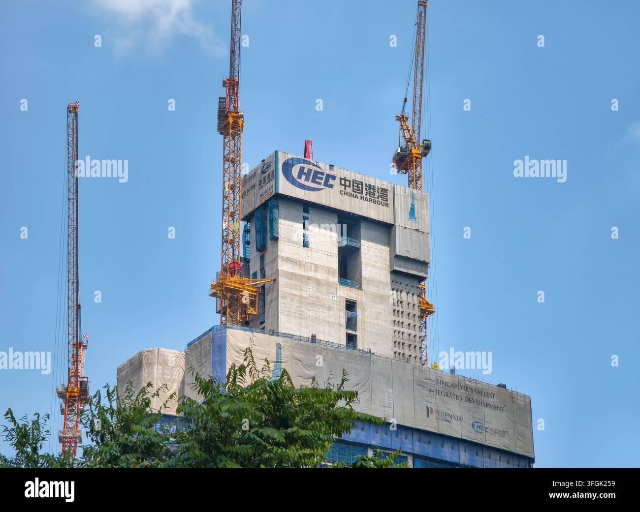 Edificio alto in costruzione con strutture centrali in cemento e gru a torre arancioni, logo della China Harbour Engineering Company (CHEC), Singapore Foto Stock