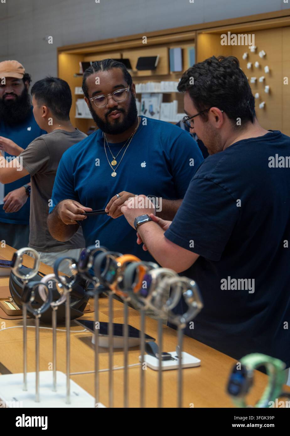 Clienti che discutono dell'Apple Watch con un assistente all'Apple Store, Fifth Avenue, New York City, USA Foto Stock