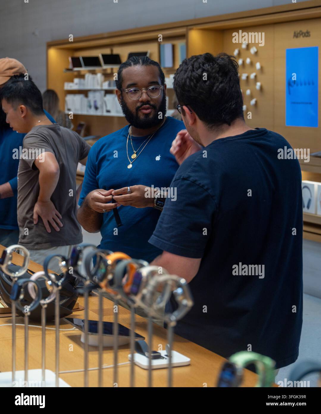 Clienti che discutono dell'Apple Watch con un assistente all'Apple Store, Fifth Avenue, New York City, USA Foto Stock
