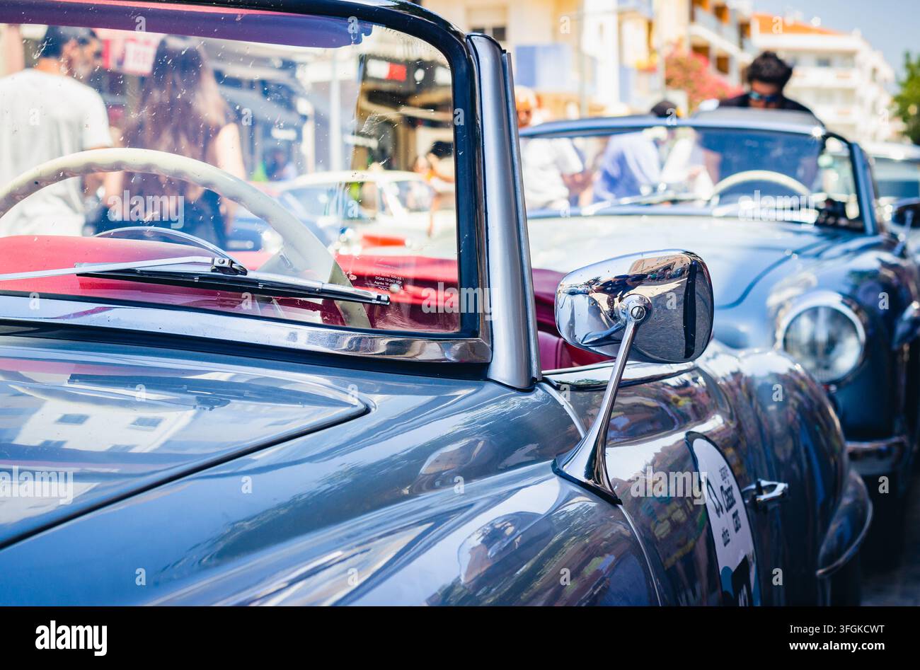 Classica auto blu vintage decappottabile parcheggiata su una strada cittadina soleggiata, con enfasi sullo specchietto laterale cromato, il parabrezza e la carrozzeria. Foto Stock