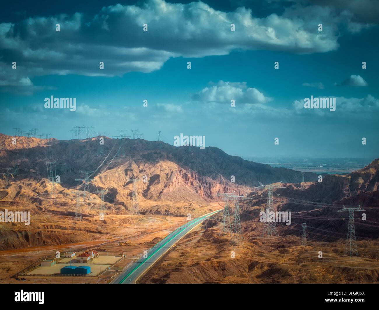 Ripresa aerea dell'area esterna del Grand Canyon di Pingshanhu. Montagne stratificate di colore marrone rossastro si estendono continuamente. Si ergono tralicci di trasmissione ad alta tensione Foto Stock
