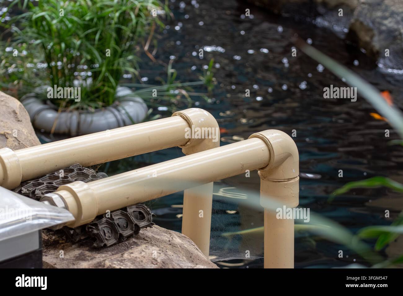 Sistema di tubi dell'acqua in PVC di plastica vicino a uno stagno artificiale Foto Stock